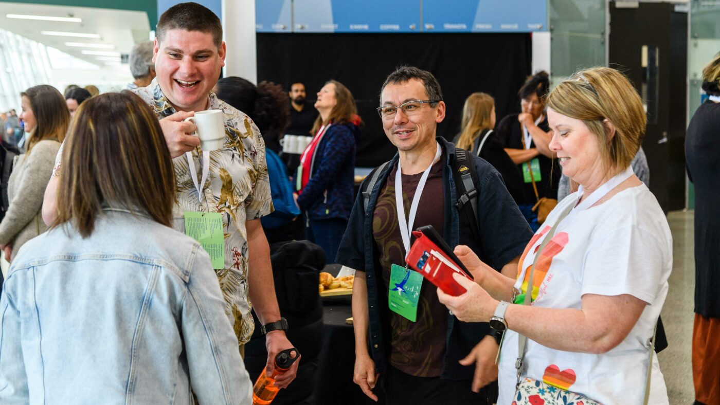 A group of members catching up over coffee in the foyer of Hui-ā-tau 2022