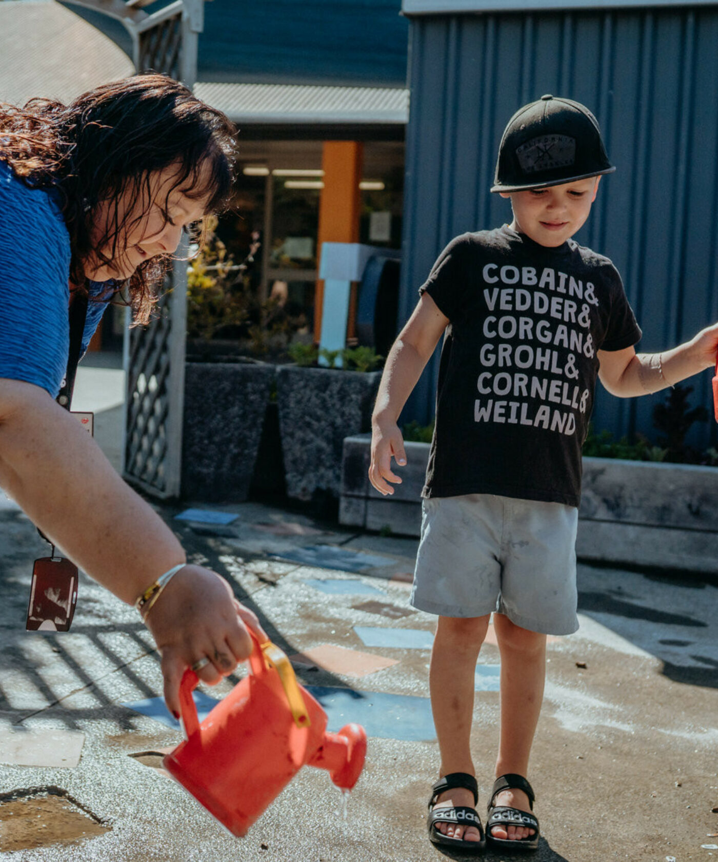 Woman plays with watering cans with a child.