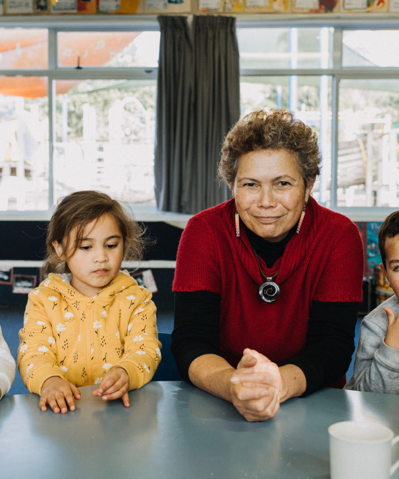 Teacher sitting at a desk with three children.