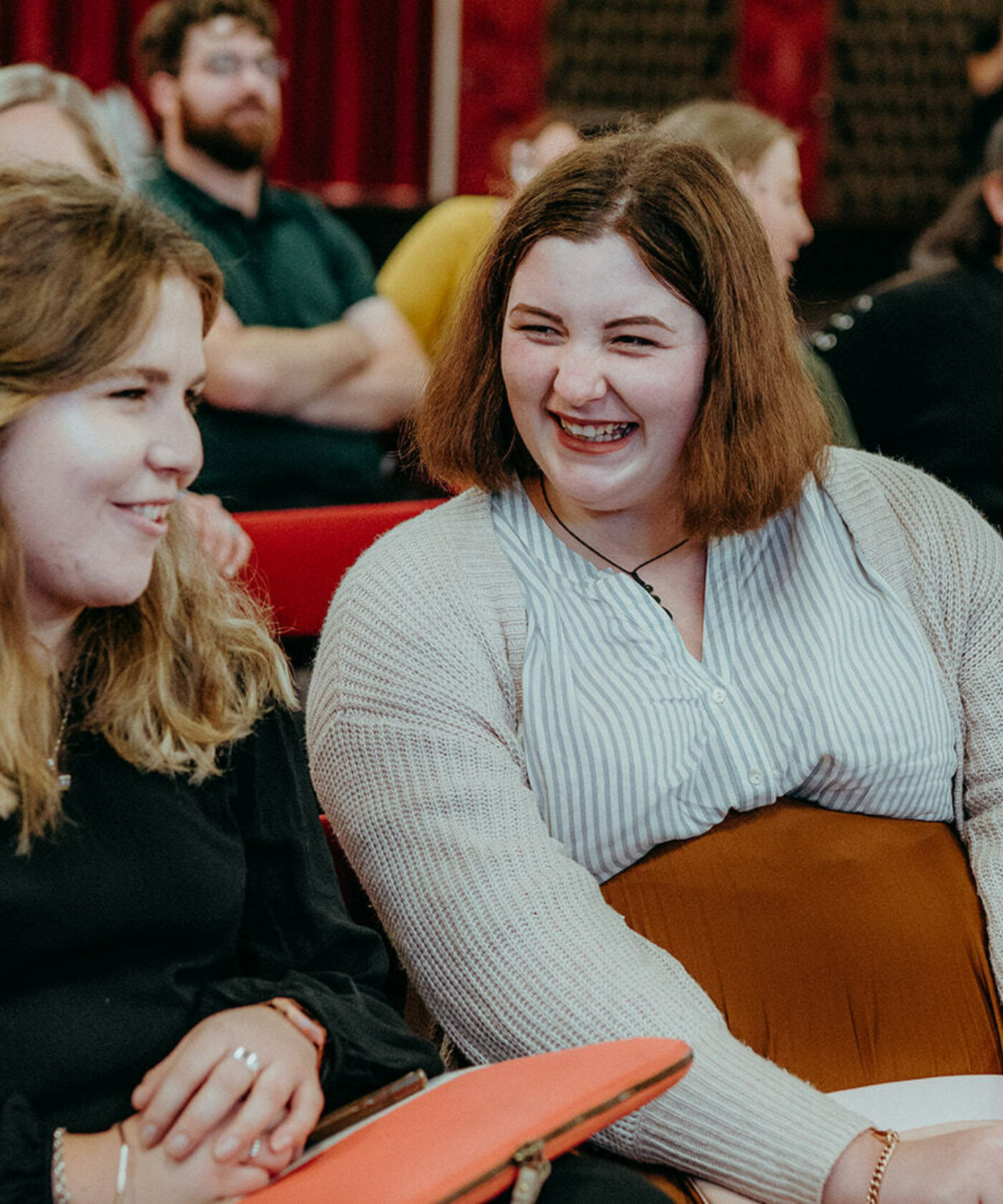 Two student members laughing with other members in the background.