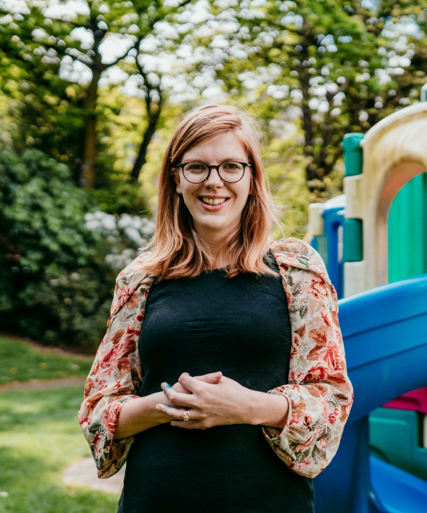 Early childhood teacher standing in front of a playground.