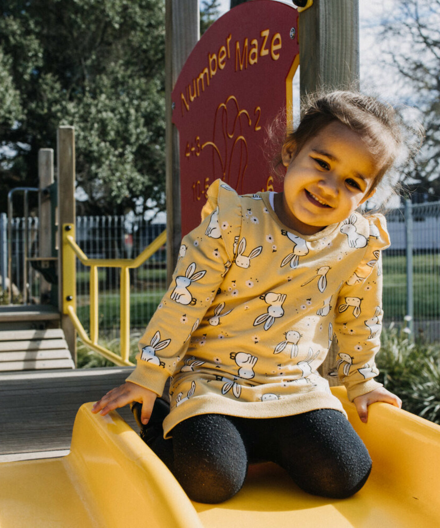 Child kneeling at the top of a slide.