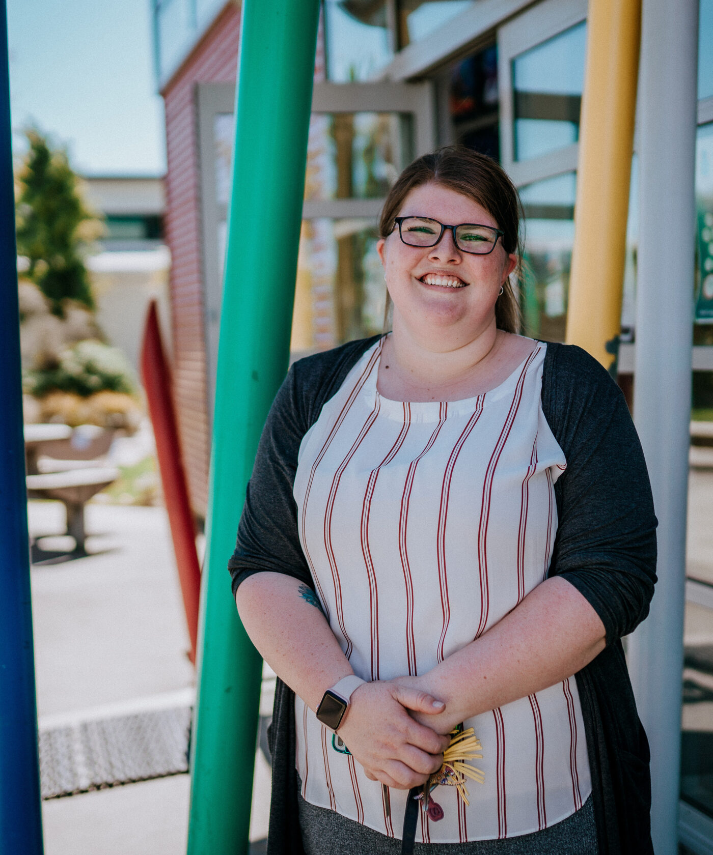 Primary teacher stands amongst multi-coloured pillars.